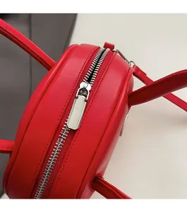 Détail d'une fermeture éclair en métal argenté sur un sac à main rond rouge élégant