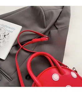 Gros plan du sac à main rouge à pois en cuir sur une veste de costume grise chic