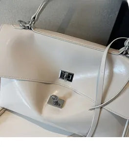 Close-up of white glossy PU leather tote bag with silver square twist-lock closure detail