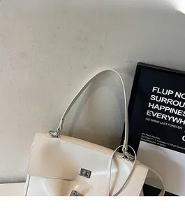Detail view of the creamy white leather tote featuring a silver twist lock and slim strap