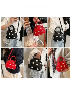 Détail du sac coquille à pois en noir et rouge avec bandoulière ajustable