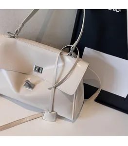 Detail view of cream-colored glossy tote bag featuring dual silver square metal locks
