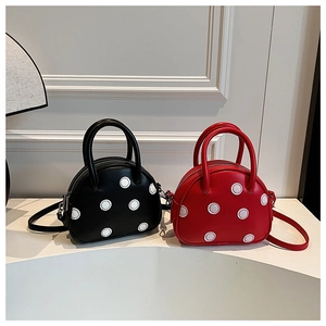 Détail de sacs coquille à pois noirs et rouges avec poignées et bandoulières amovibles