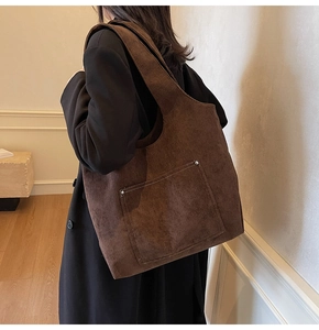 Brown corduroy tote bag shown on shoulder featuring vintage texture and front pocket