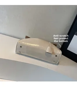 Close-up of four silver protective metal studs on the bottom of the cream tote bag