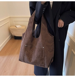 Detail of dark brown corduroy tote bag showing front pocket with metallic rivets