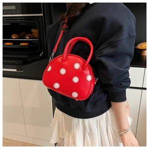 Détail d'un sac coquillage rouge à pois porté par un mannequin dans un cadre de vie