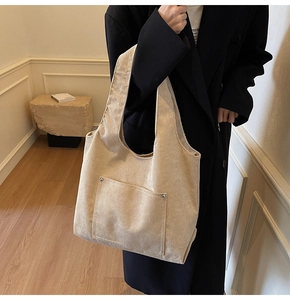 Detail of beige corduroy tote bag with silver rivets on the square front pocket
