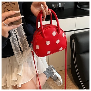 Détail du sac à main rouge en cuir à pois avec poignée et fine bandoulière réglable