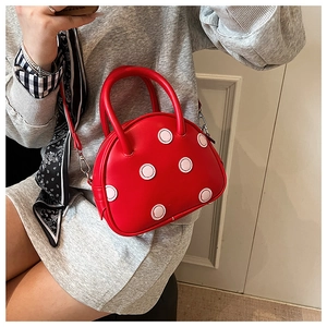 Vue détaillée d'un sac rouge à pois porté en bandoulière sur un fond intérieur neutre