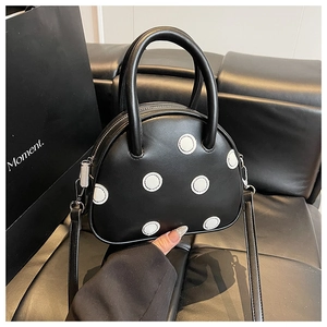 Détail d'un sac à main en cuir noir à pois blancs avec une poignée supérieure