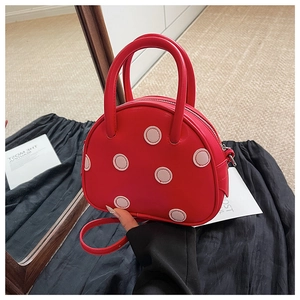 Détail du mini sac rouge à pois en cuir lisse avec des poignées rondes et robustes
