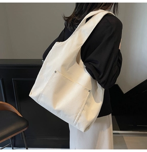 Detail of white corduroy tote bag showing metal rivets and spacious front pocket