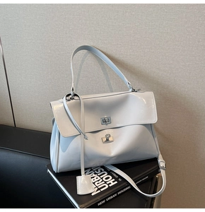 Detail of light grey glossy tote bag with silver rotary lock on minimalist books