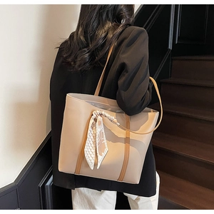 Detail of minimalist tote bag in beige and coffee leather with elegant patterned silk scarf