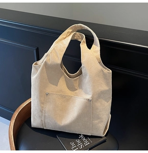 Detail view of corduroy tote bag showing metal rivet accents and front pocket texture