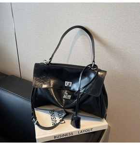 Detail of black glossy tote bag with silver turn-lock clasp and detachable strap