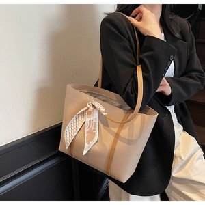 Close-up of beige tote bag with brown leather straps and decorative floral silk scarf