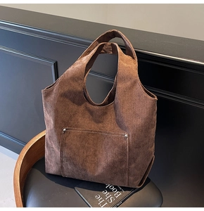 Detailed texture of dark brown corduroy tote bag with front pocket and metal rivets