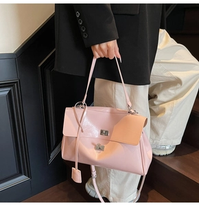 Close-up of pink patent leather tote bag with metal turn-lock and matching square charm
