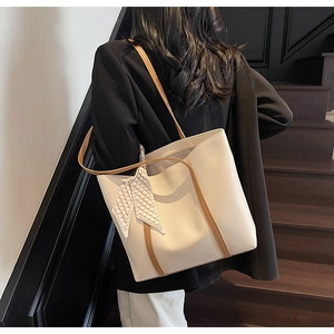 Detail of cream tote bag with brown straps and checkered silk scarf accessory