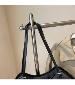 Détail de la large bandoulière en cuir noir et de la boucle en métal argenté d'un grand sac
