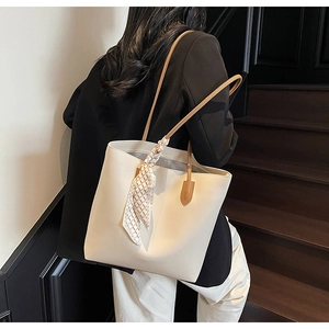 Detail of cream tote bag with plaid scarf and dual straps worn on shoulder