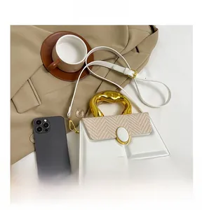 Detail of herringbone weave flap and irregular gold metal handle on a white crossbody bag