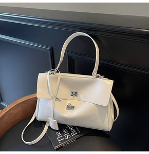 Detail of cream glossy tote bag with silver metallic twist lock and adjustable strap