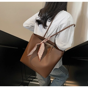 Detail of dark brown leather tote bag with stylish plaid scarf on handle in street setting