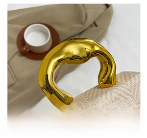 Detail of elegant gold curved metal handle on a stylish woven contrast handbag