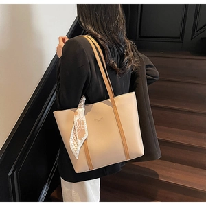 Detail of a large beige tote bag with brown contrast straps and a vintage floral scarf