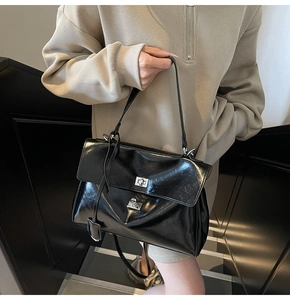 Detail of black wax leather tote bag with silver square lock and dual shoulder straps