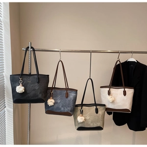 Detail of four-color tote bags in dark grey, blue, green and beige with plush charms