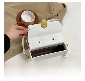 Detail of white box bag interior with brown lining and gold-tone twist lock closure