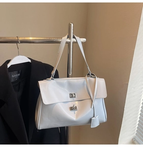 Close-up of light gray glossy leather tote with dual metal twist locks and shoulder strap