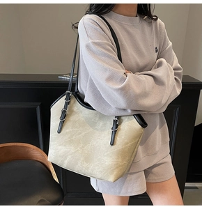 Détail du sac cabas beige avec bordure en cuir noir et boucle métallique sur la bandoulière