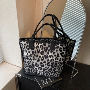 Chic leopard print canvas tote bag with black straps in a minimalist indoor setting