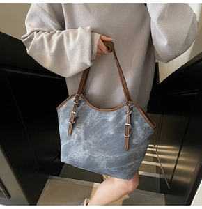Détail du sac cabas à texture marbre bleu avec bandoulière en cuir marron et boucle