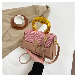 Detail of elegant beige leather bag with woven flap and artistic gold wavy handle
