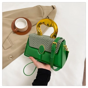 Detail of green box bag with unique gold handle and houndstooth flap pattern