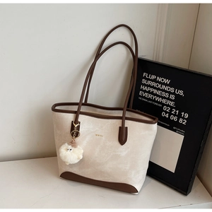 Detail of off-white tote bag with brown leather straps and WWTU logo on a marble surface