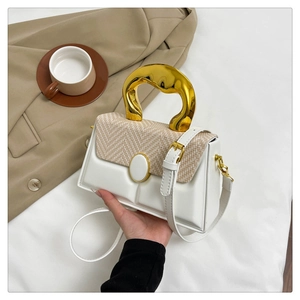 Detail of a chic white handbag featuring a unique irregular gold metal handle and woven flap