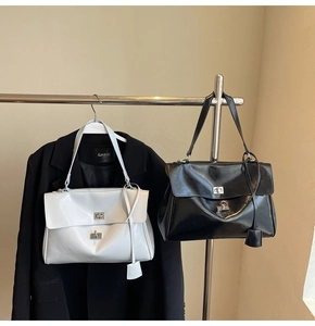 Detail of stylish glossy leather tote bags with metal turn-lock hanging on a rack
