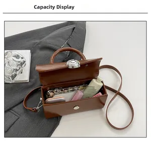 Internal capacity view of brown leather box bag showing phone and lipstick storage