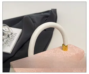 Detailed close-up of pink snake skin pattern texture and white leather handbag handle