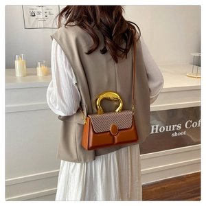 Detail of caramel leather bag with herringbone flap and large gold metal handle