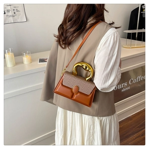 Detail of contrast stitching on retro crossbody bag with a curved gold metal handle