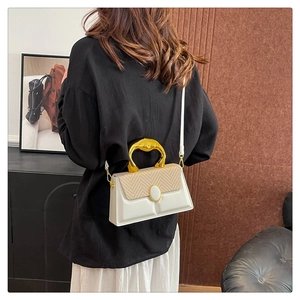 Detail of white and beige crossbody bag with woven texture and gold metal handle