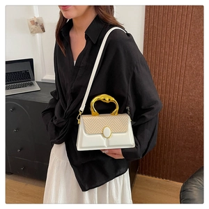 Detail of artistic gold metal handle on contrast paneled leather and woven crossbody bag